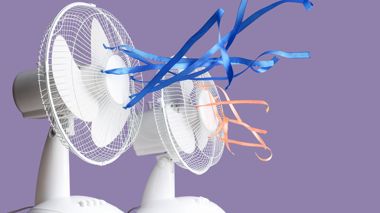 Two table fans with fluttering ribbons against a violet background