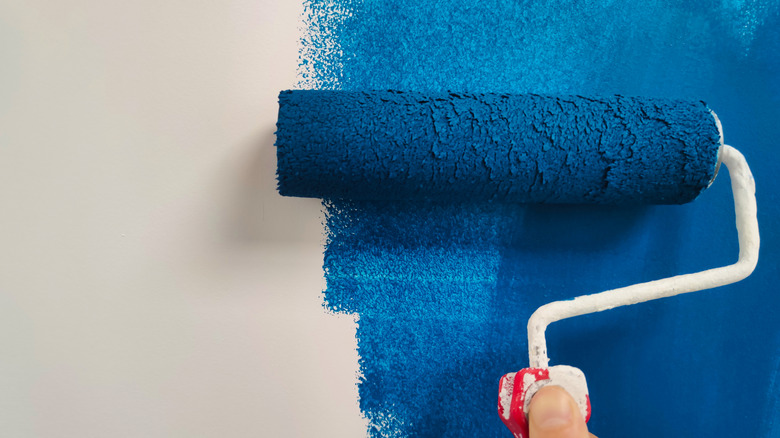 Roller running blue paint on a white wall