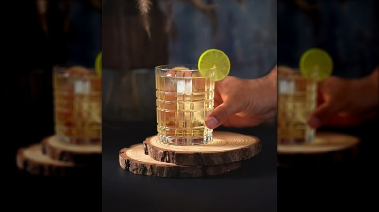 Hand holding glass of 7&7 cocktail garnished with lime round