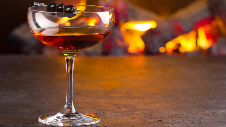 A Manhattan cocktail with a fireplace in the background