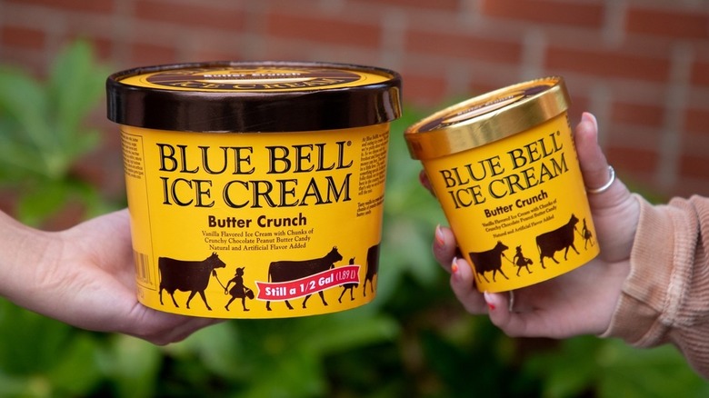 Two people holding containers of Blue Bell Butter Crunch ice cream