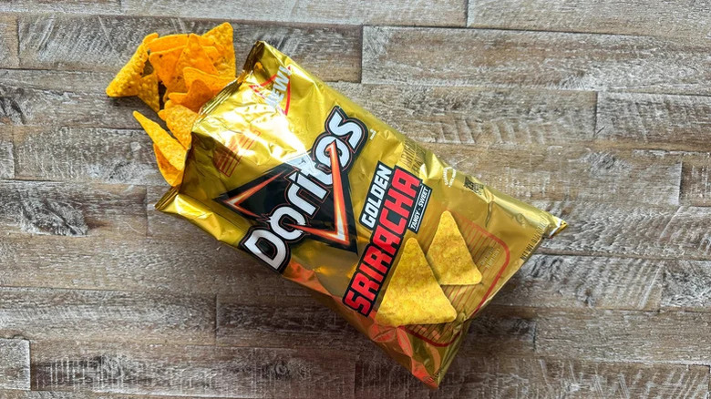 An open bag of Golden Sriracha Doritos with some chips spilling out