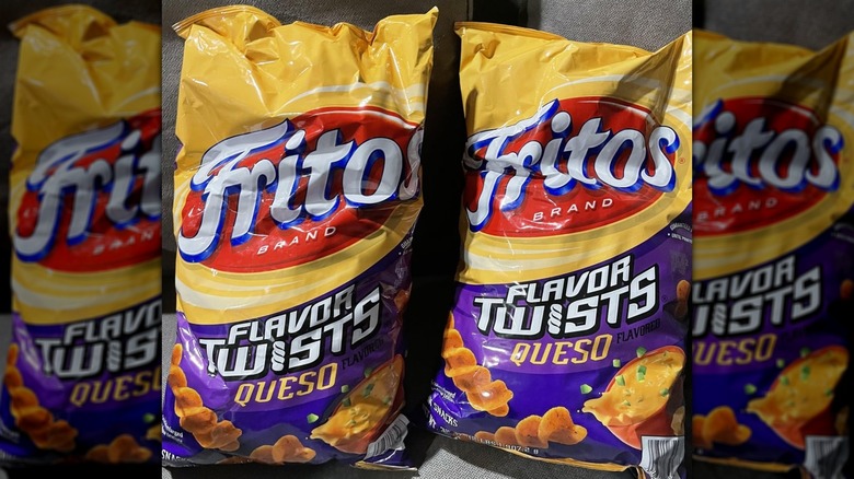 Two bags of Fritos Flavor Twists Queso displayed on a gray sofa