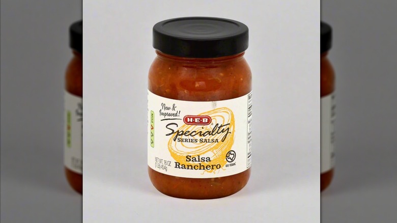 Jar of H-E-B Specialty Series salsa ranchero on a white mirrored background