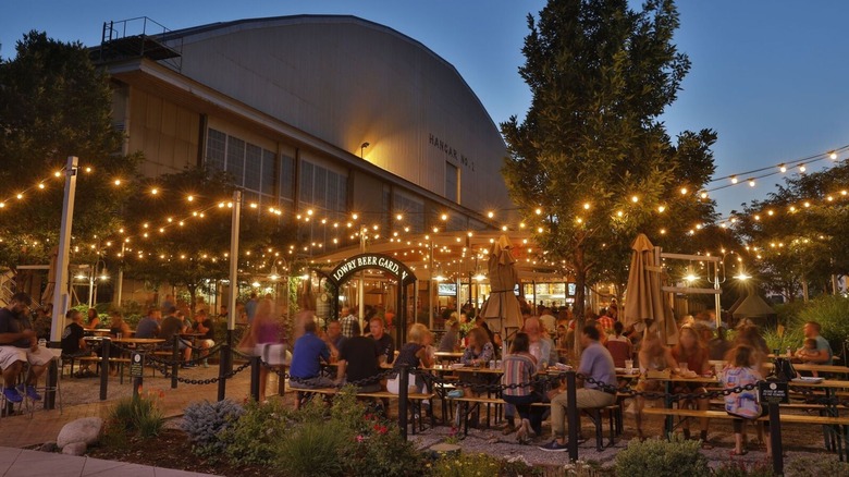 People at tables outside in the evening under lights