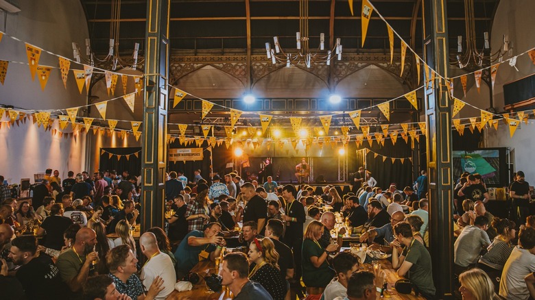 Indoor view of seated crowds and hanged yellow pennants at Swansea Craft Brew Festival