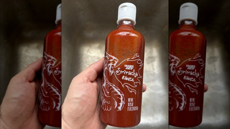 Hand holding bottle of Tradre Joe's Sriracha sauce