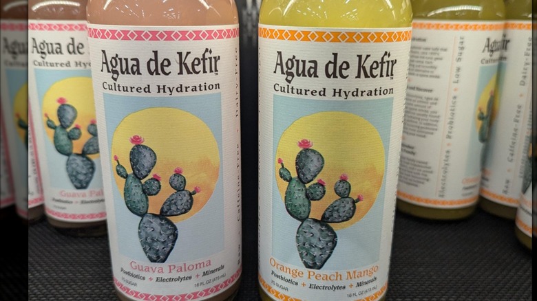 Bottles of Agua de Kefir Guava Paloma and Orange Peach Mango on a shelf