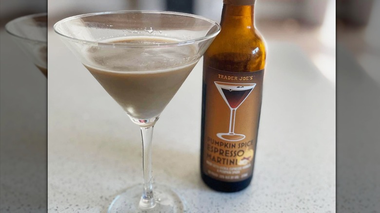 A partially filled martini glass next to a brown bottle of Trader Joe's pumpkin spice espresso martini