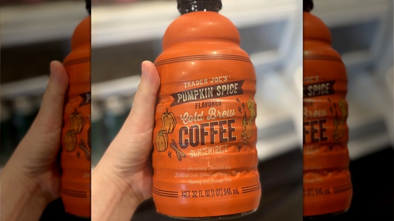 A hand holding an orange bottle of Trader Joe's pumpkin spice flavored cold brew coffee concentrate
