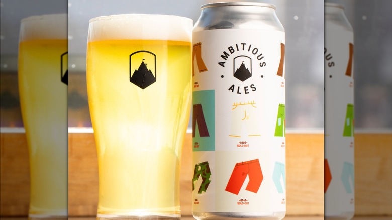 A pint of beer next to a can of Ambitious Ales Calico Cut IPA.