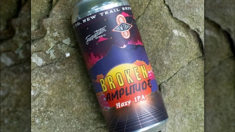 A colorful can of Broken Amplitude beer on a rocky surface.
