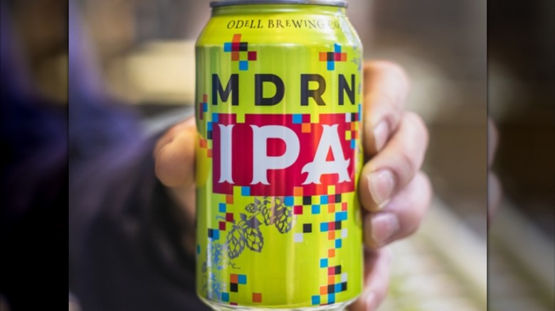 Hand holding a can of MDRN IPA beer.
