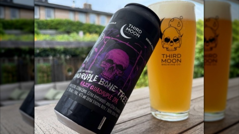 A can of Third Moon Brewing Company Sextuple Dry Hopped Quadruple Bone Tree leaning against a full pint glass on a table.