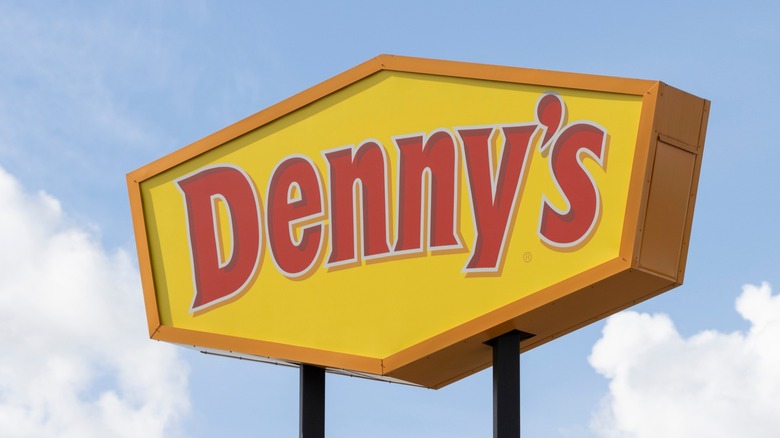 Denny's sign against a blue sky with a few clouds