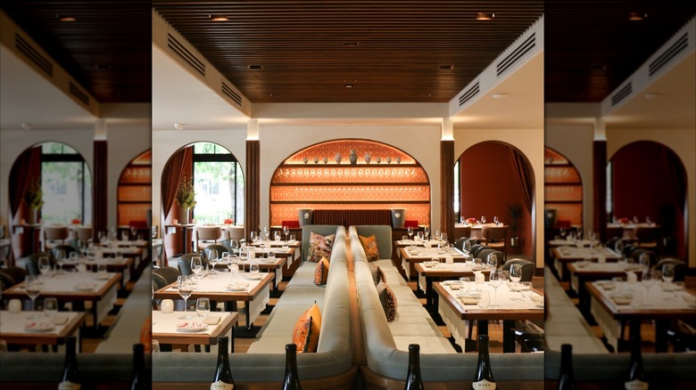 Long green booth with tables and back wall lit with glasses