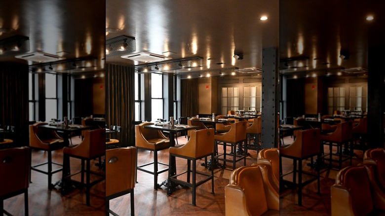 Elevated beige armchairs at tables in dim lit restaurant