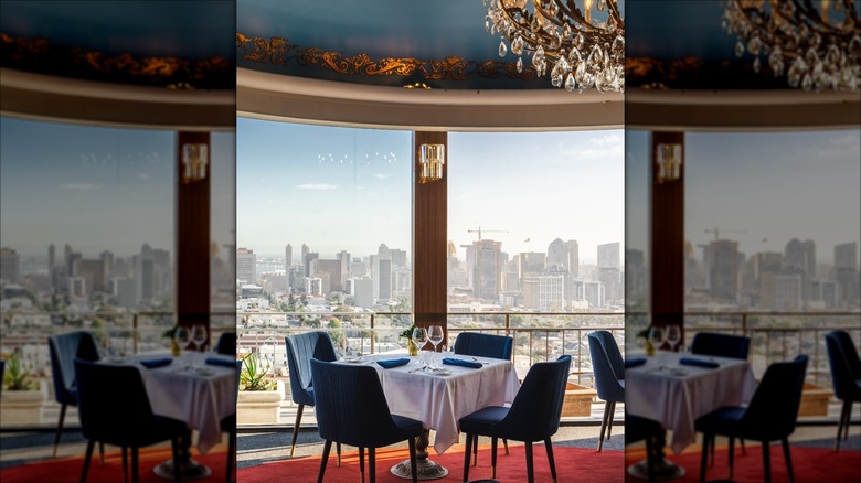 Table with white tablecloth, four blue chairs, stunning sky-high exterior view