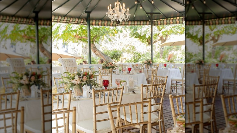 Table with white tablecloths, flowers, small chandelier overhead under rotunda