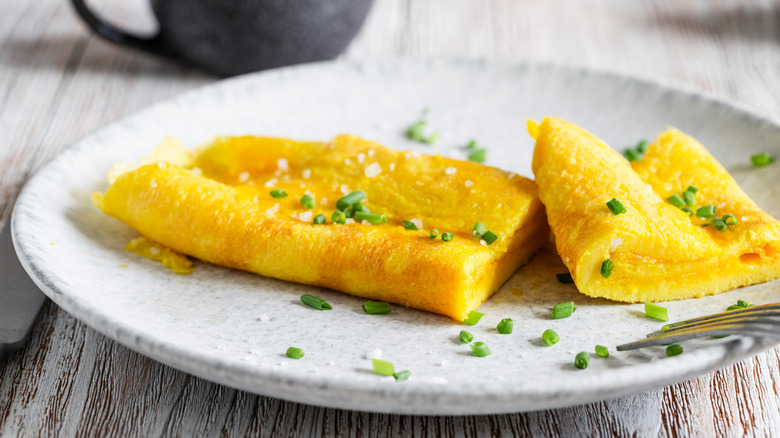 French omelet on plate cut in half and sprinkled with salt and chives
