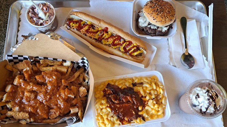 Food challenge with foot-long hot dog, mac and cheese, poutine, burger, and two desserts