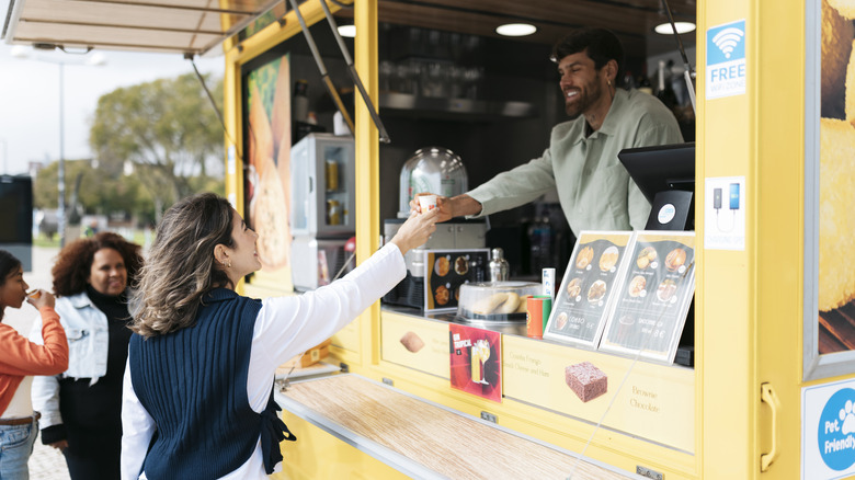 Woman getting drink from food truck.