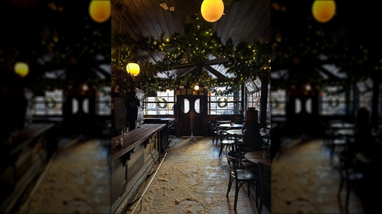 Interior of McSorley's with sawdust floors, tables, bar, and dim lights