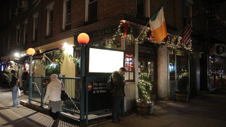 Exterior of Peter McManus Cafe at night with people on sidewalk