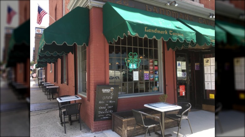 Exterior of Landmark Tavern with green awning and tables on sidewalk