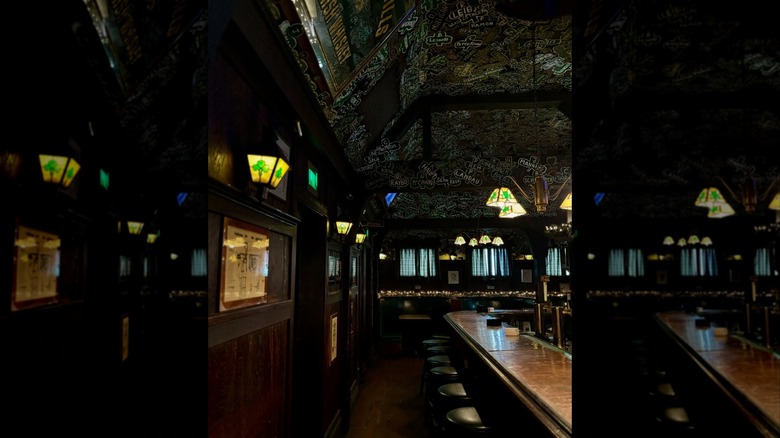 Dimly lit interior with bar, stools, and shamrocks on ceiling