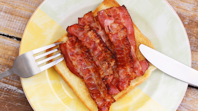 crispy bacon on toast on plate with knife and fork