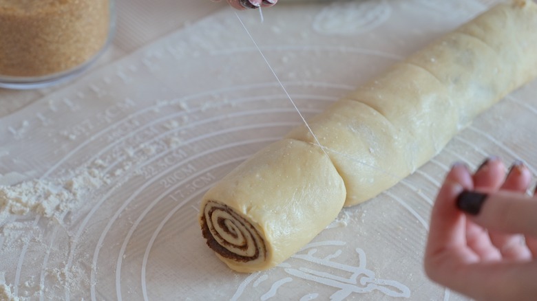 woman hands cuts a twisted dough with a thread