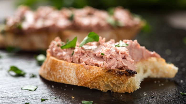 Bitted liverwurst on bread sprinkled with green herbs