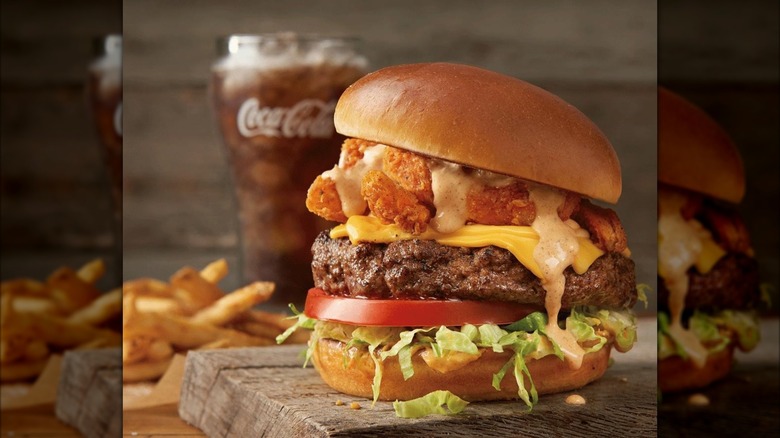 The Bloomin' Burger from Outback Steakhouse on wooden board with fries and cup of Coke in background