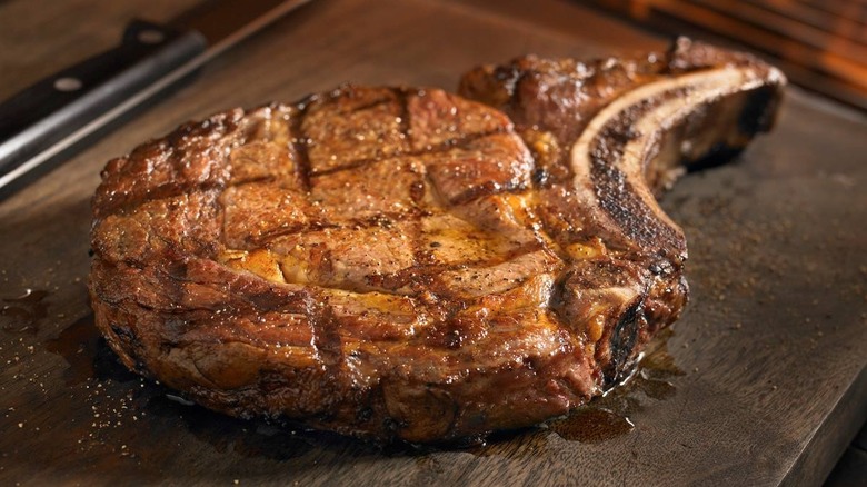 Bone-In ribeye steak from Outback Steakhouse on dark wooden cutting board