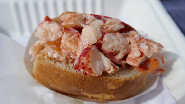 Close-up of a lobster roll wrapped in paper and in a white container