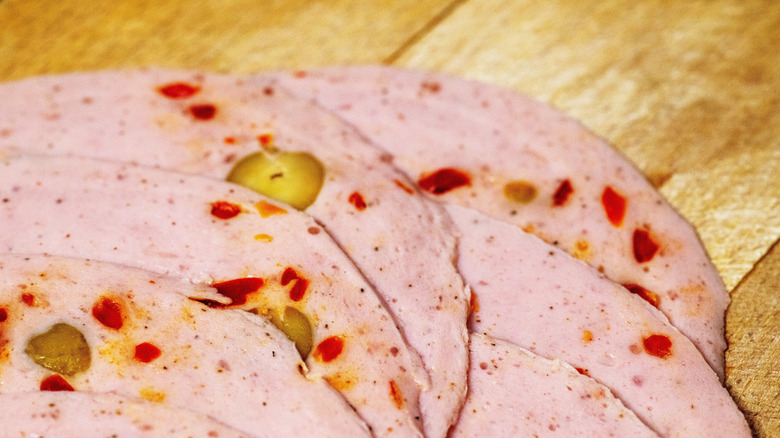 A close-up of slices of olive loaf on a wooden cutting board