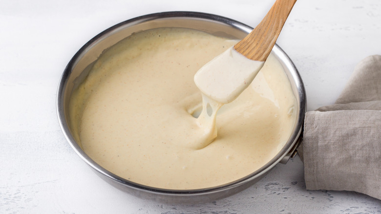 Bowl of cheese sauce with wooden spatula