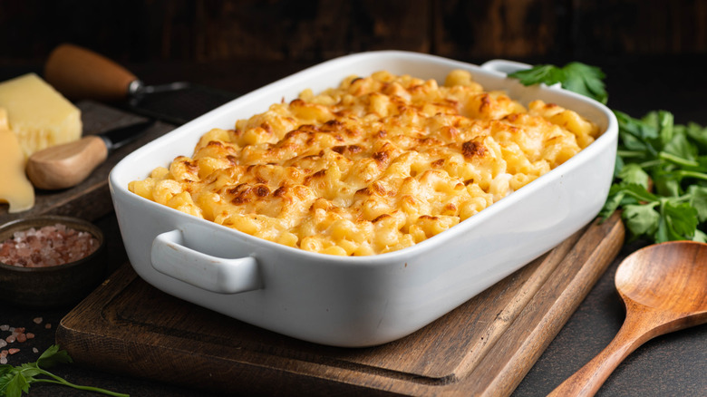 Mac and cheese in white baking dish on wooden board
