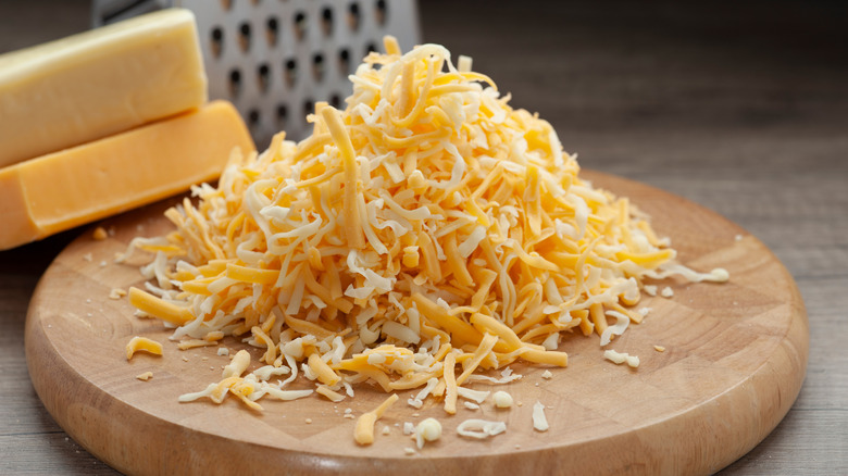 Shredded cheddar and mozzarella on wooden cutting board