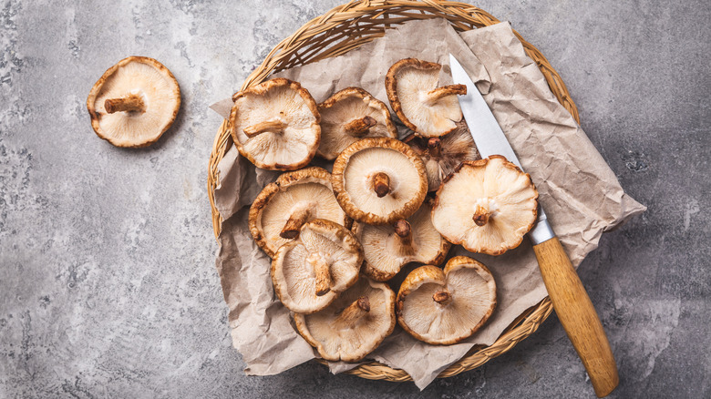 Shiitake mushrooms in parchment-lined basket with knife