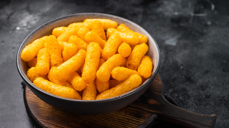 Bowl of cheese puffs on wooden board