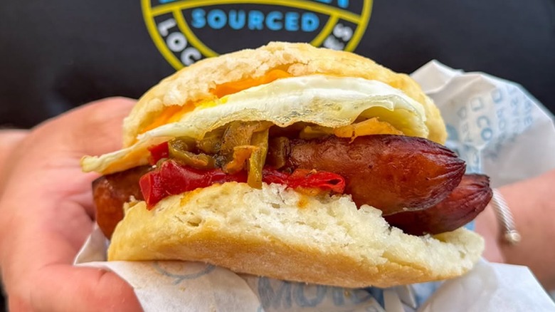 Someone holding a smoked sausage biscuit from Biscuitville