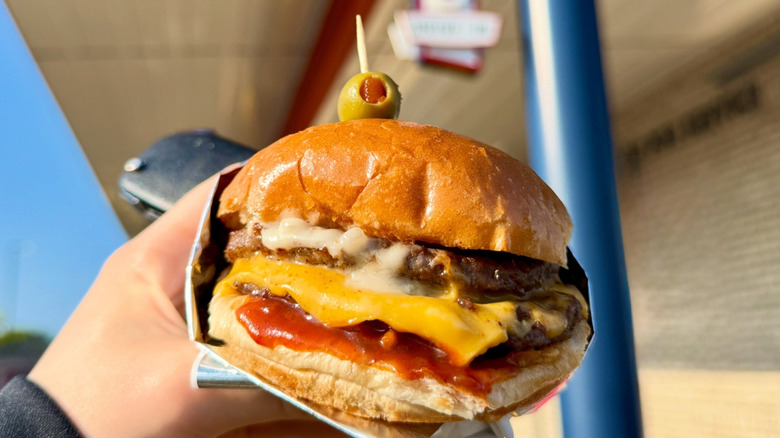 Someone holding a hamburger from Swensons Drive-In