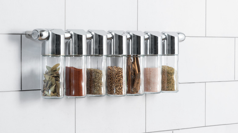 Decorative spice rack hanging on white tiled wall