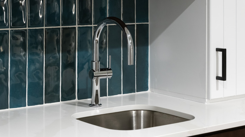 Dark blue tile kitchen backsplash with sink