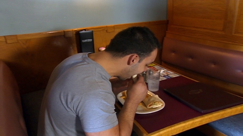 Man eating wrap in restaurant booth
