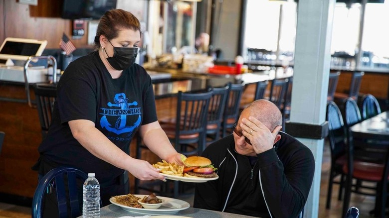 The Anchor employee wearing facemask serving food to Robert Irvine