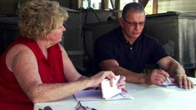 Robert Irvine sits with Whistle Stop owner Linda Todd with paperwork at a white table
