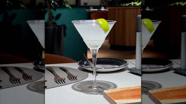 mirrored image of Kamikaze cocktail in martini glass with lime wedge on set restaurant table
